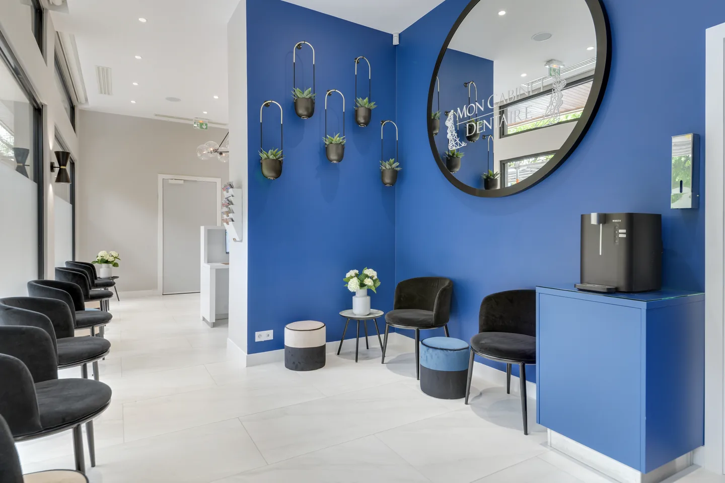 L’espace d’accueil du cabinet, avec son mur bleu et son miroir rond.