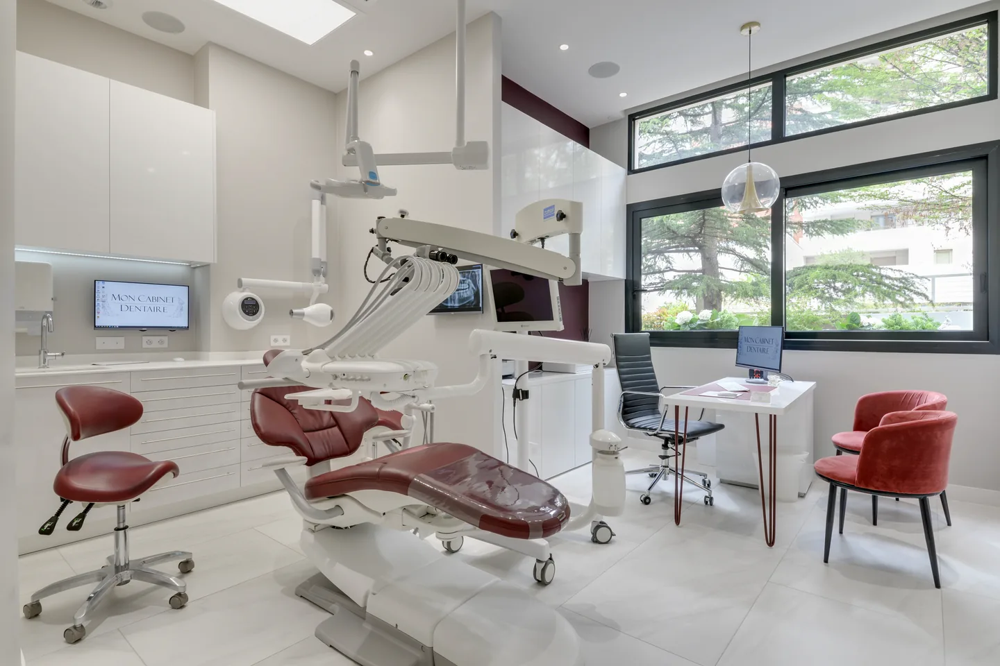 Une salle de soins du cabinet, ouverte sur les arbres par de grandes fenêtres.