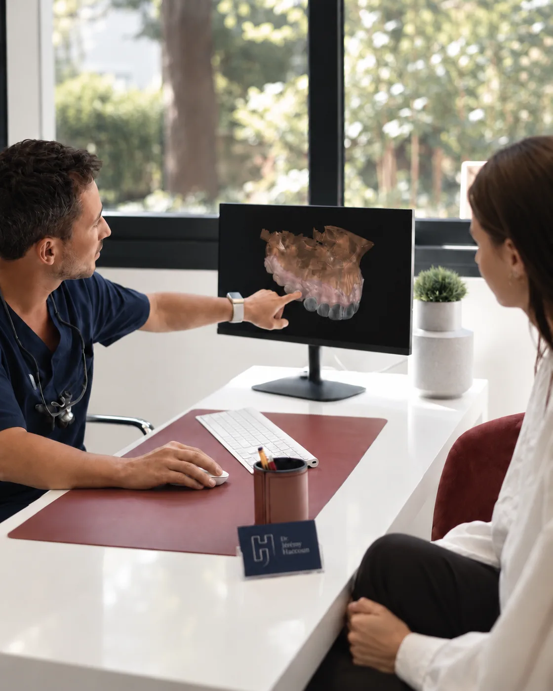 Dr Jérémy Haccoun showing a patient a digital arch model on screen.