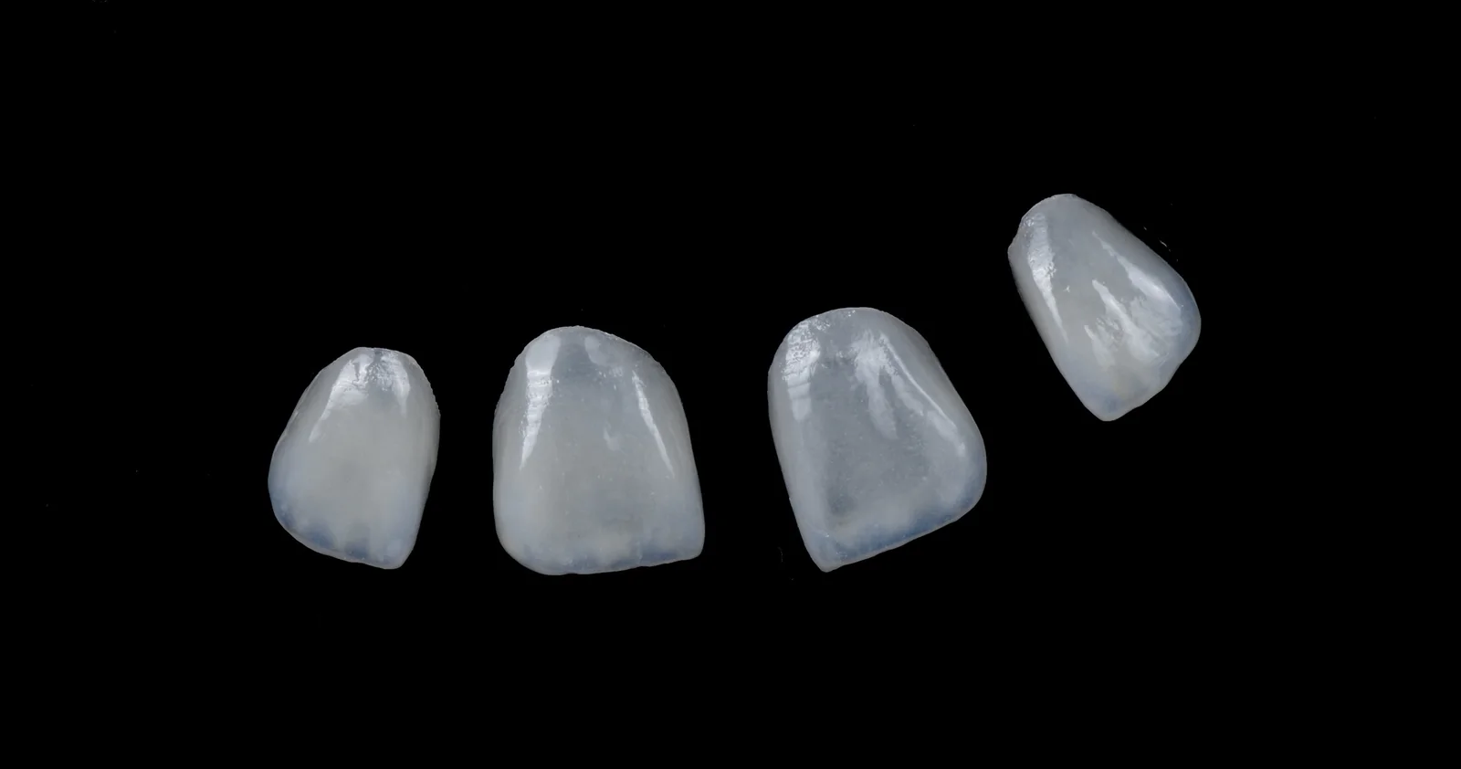 Quatre facettes céramiques feldspathiques montrant leur translucidité